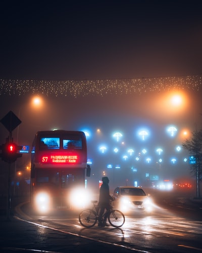 穿黑夹克的人晚上在路上骑自行车